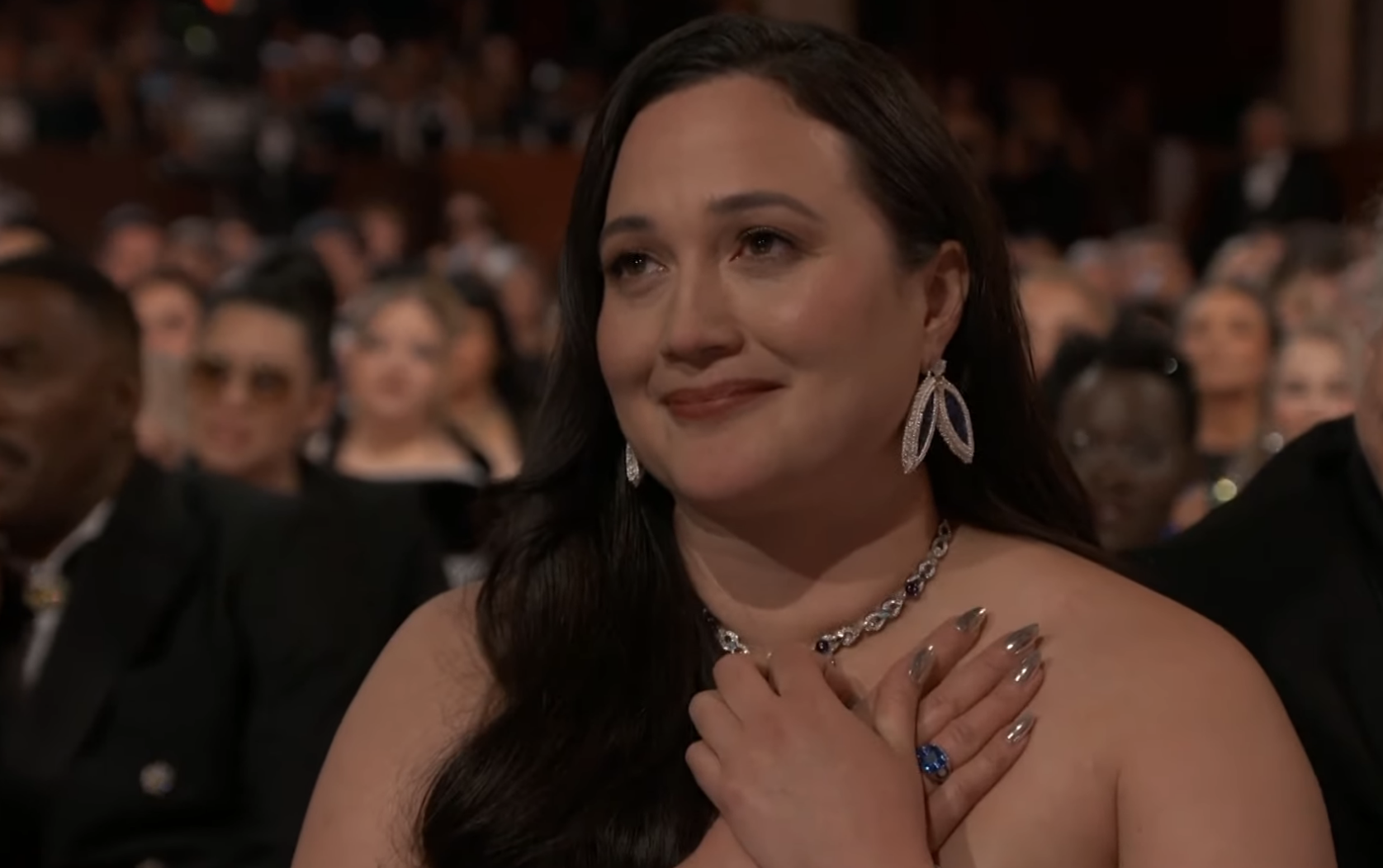 Lily at the Oscars, emotional, in the audience, wearing an elegant dress and drop earrings