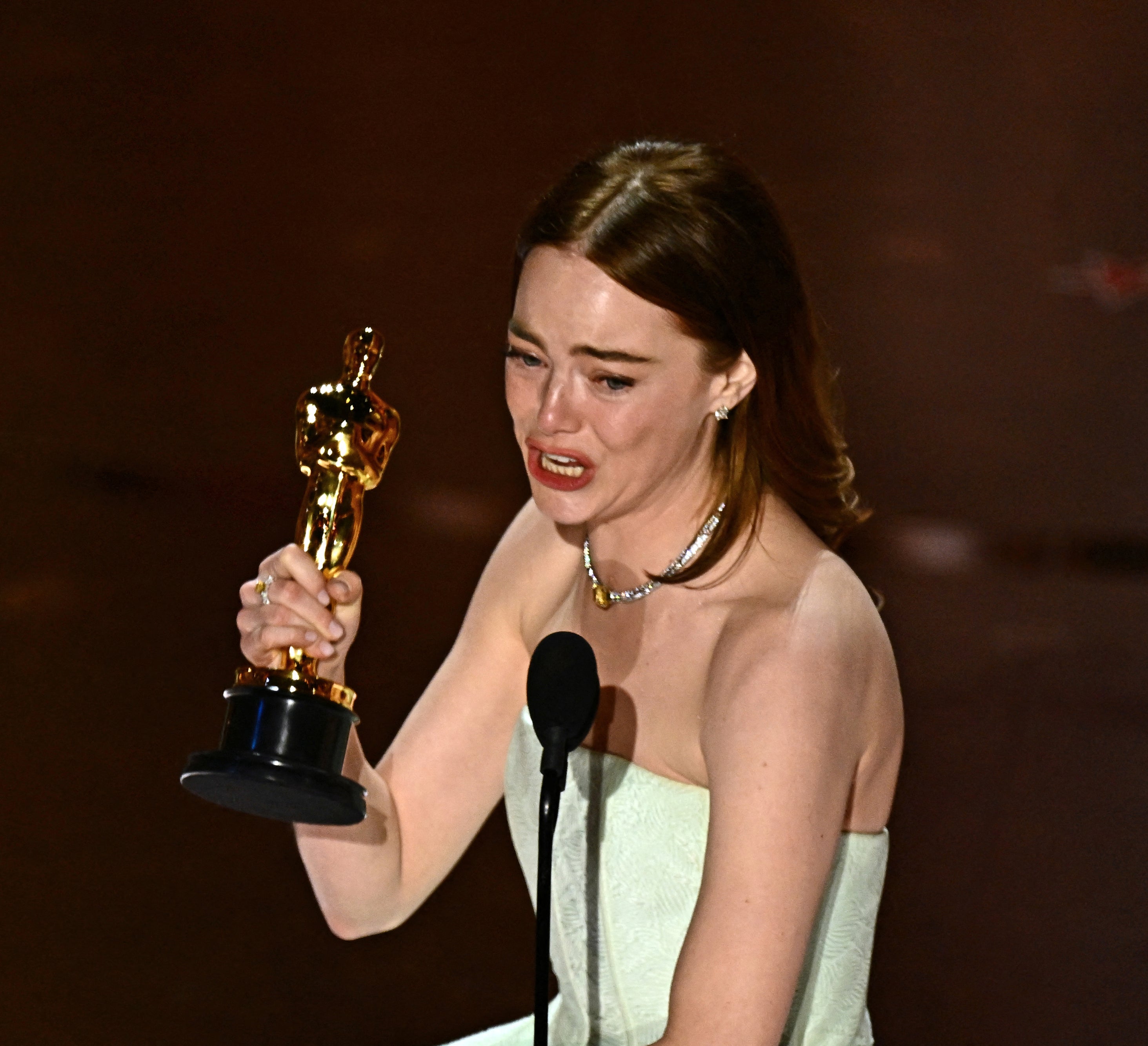An emotional Emma holding up her award onstage