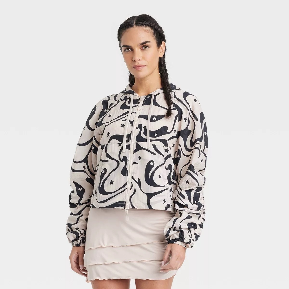 Model in the black and white zip up windbreaker, patterned with swirls and small black stars