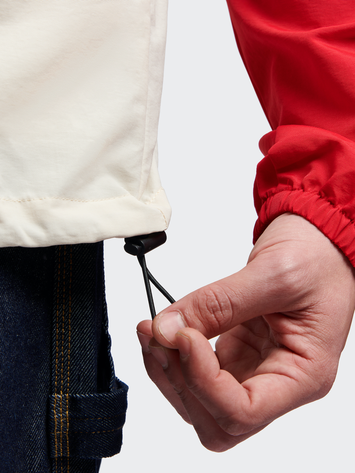 Close-up of a person tightening the drawstring on a hooded jacket