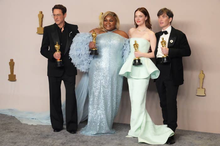 Four Oscar winners posing with their awards, two men on the ends, two women in the center, dressed in formal evening wear