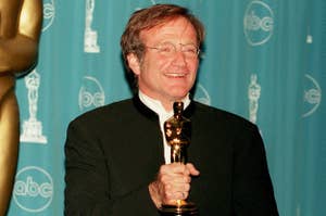 Person holding an Oscar award, smiling, with a backdrop of logo-covered screens