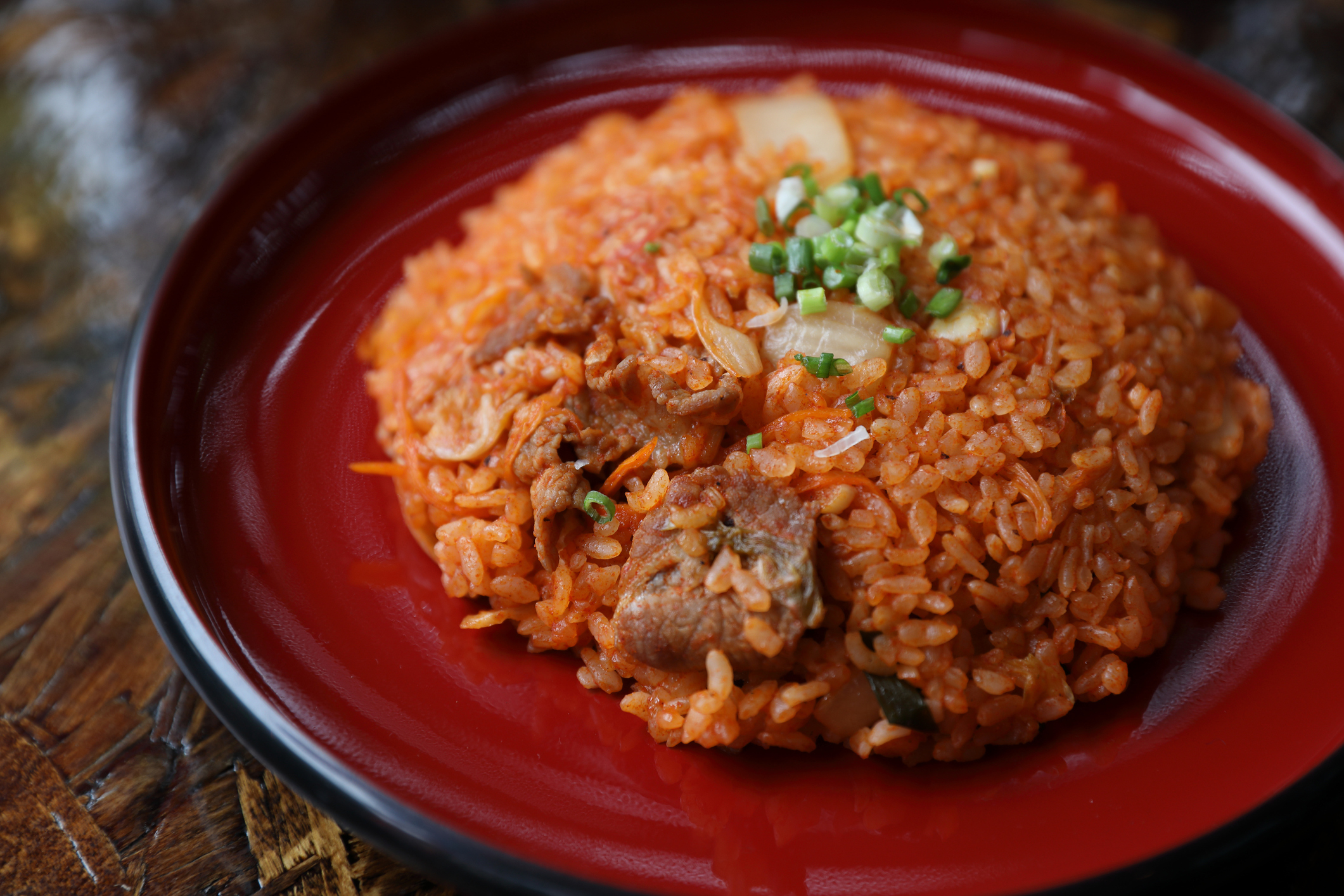 A plate of jollof rice with vegetables and meat, garnished with green onions