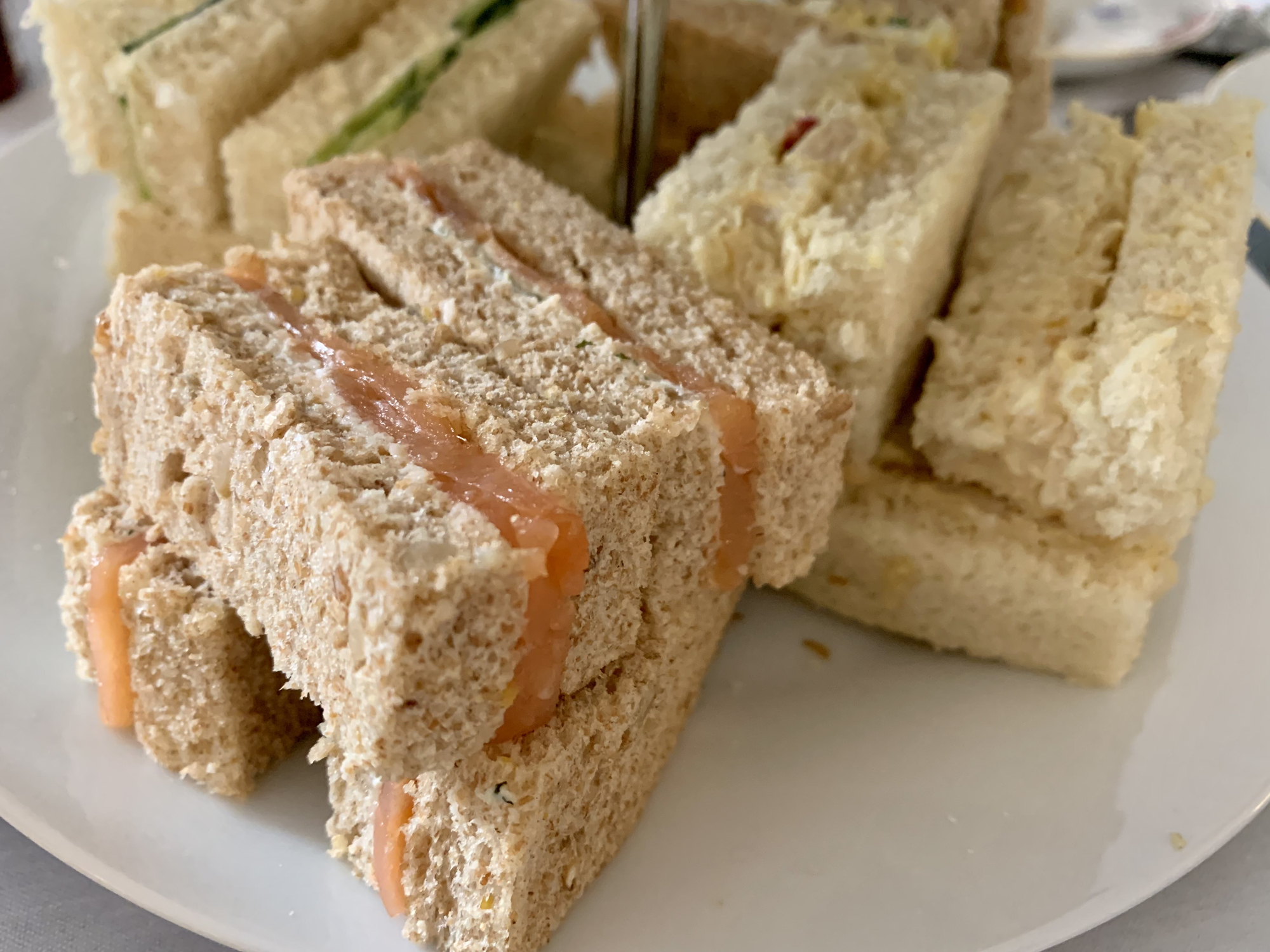 A plate of assorted cut sandwiches, including salmon and cucumber