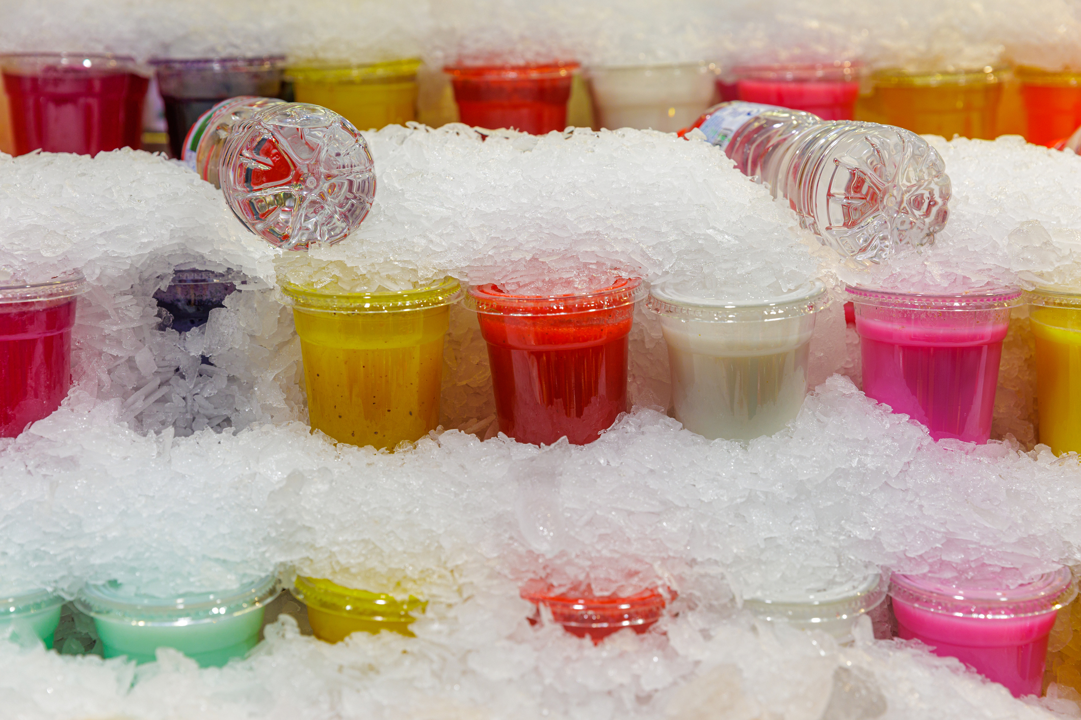 Rows of colorful frozen drinks on ice