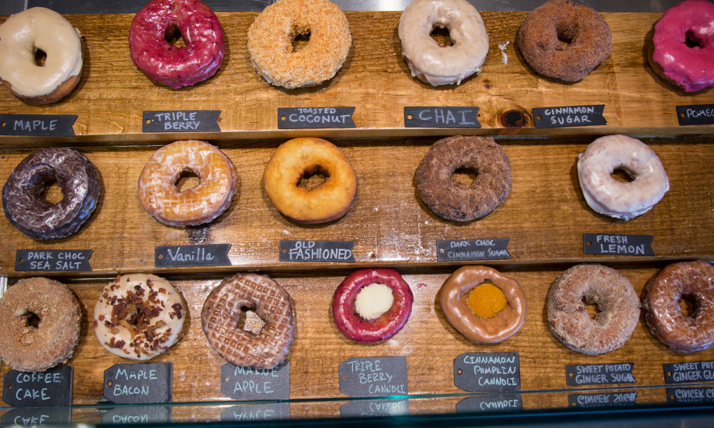 Assorted donuts on display with labeled flavors such as Maple, Vanilla, and Cinnamon