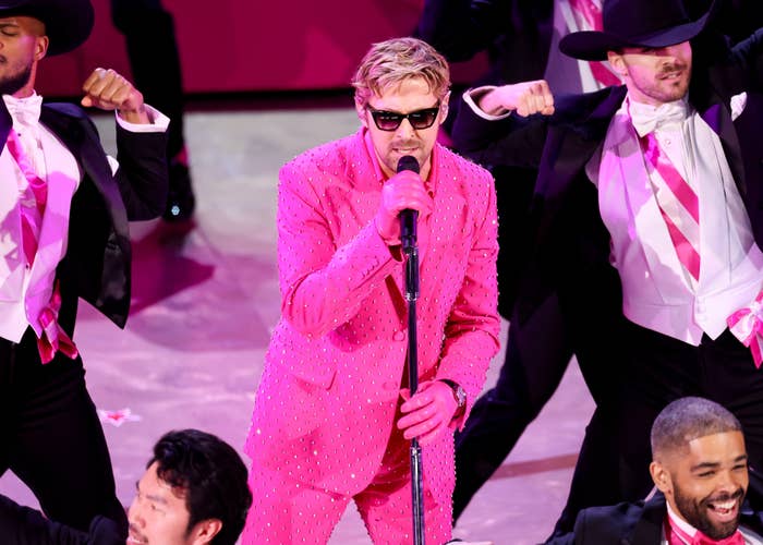 Ryan in a sparkly pink suit and sunglasses performing onstage with backup dancers
