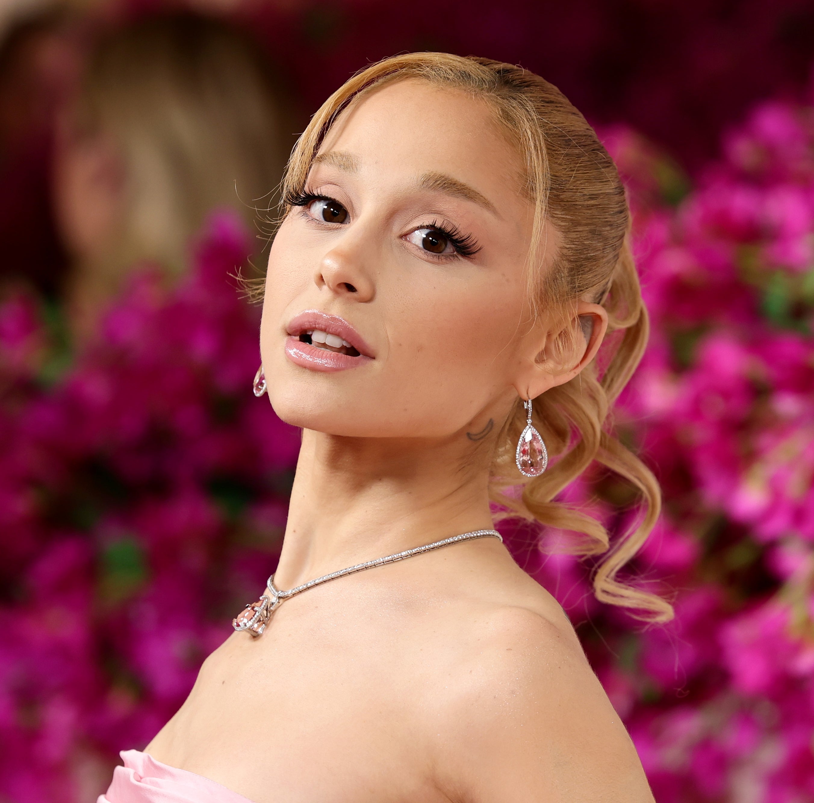 Ariana Grande poses at the Oscars, wearing a strapless gown with sleek hairdo and statement jewelry