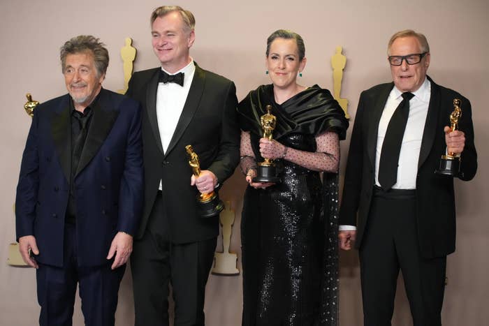 Al Pacino posing with Christopher Nolan, Emma Thomas, and Charles Roven posing with their awards for Oppenheimer