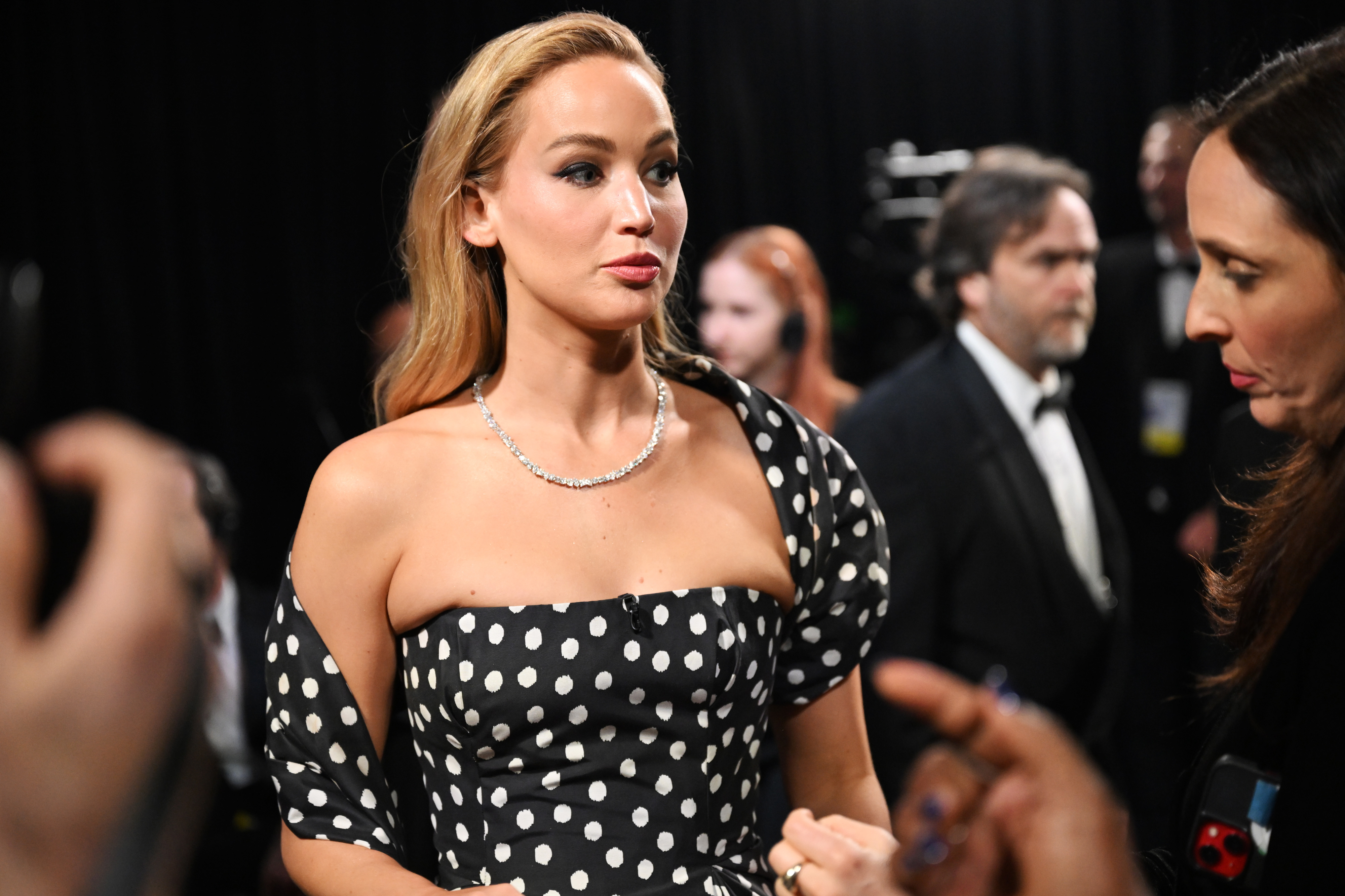 Jennifer in a polka dot outfit with a necklace converses backstage at an event