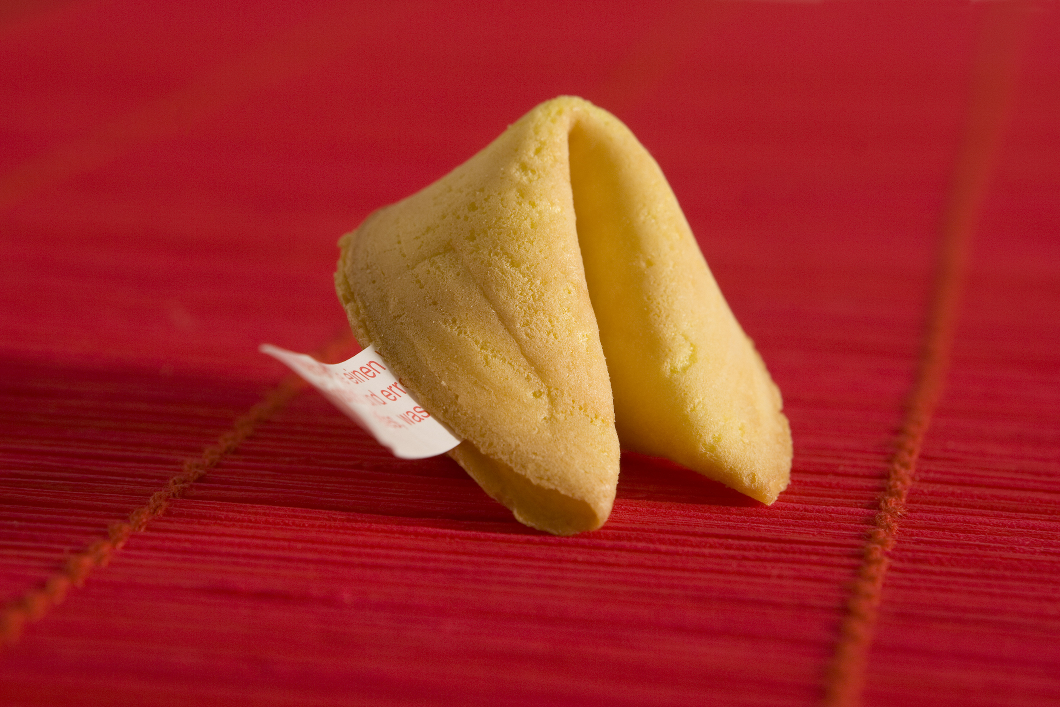 Fortune cookie cracked open with visible paper fortune on a textured surface