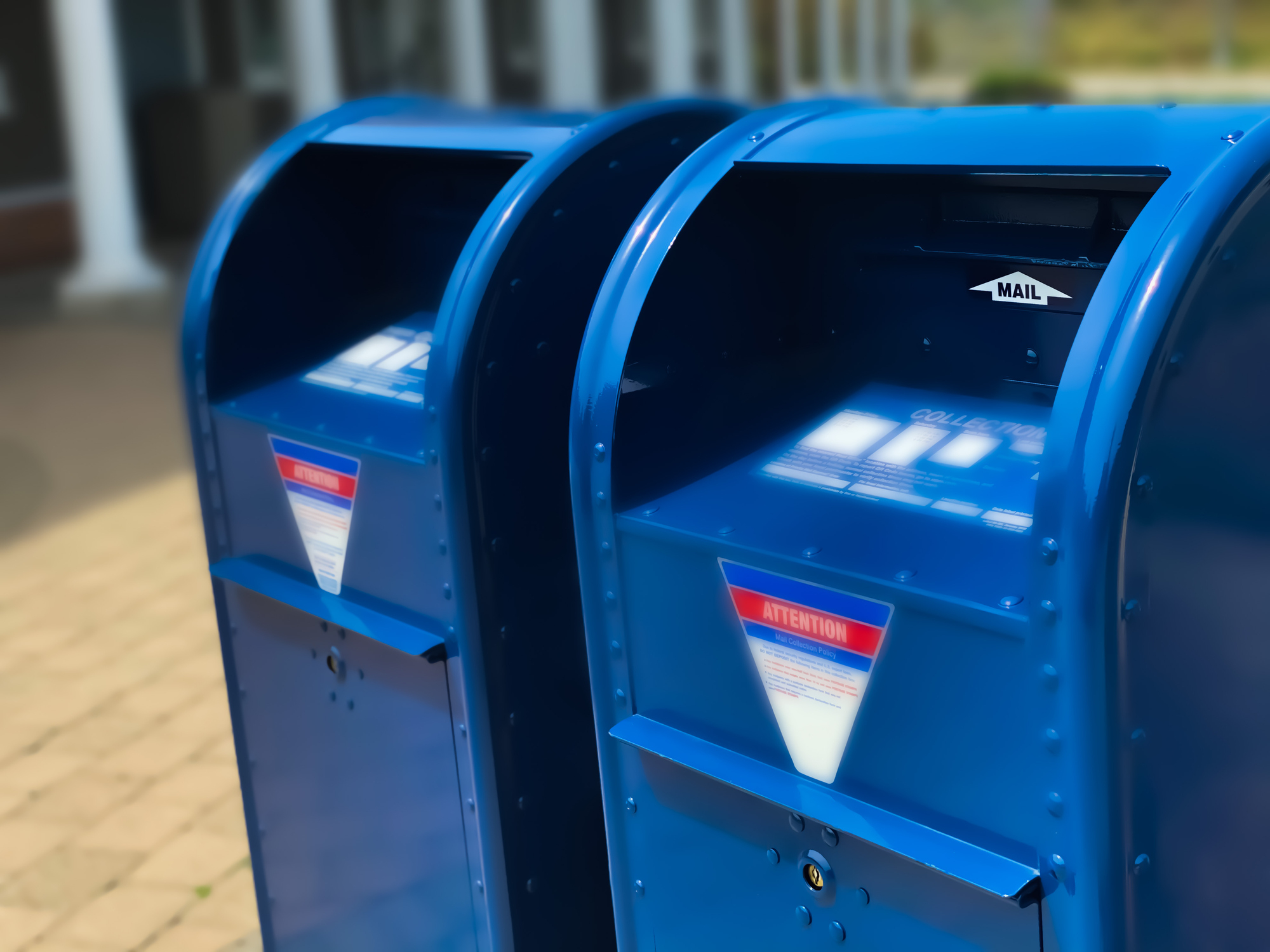 Two blue USPS mailboxes side by side on a sidewalk