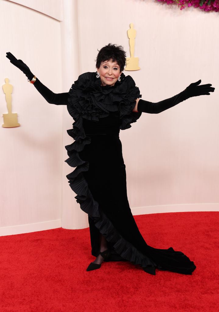 Rita Moreno strikes a playful pose in a black ruffled gown on the red carpet