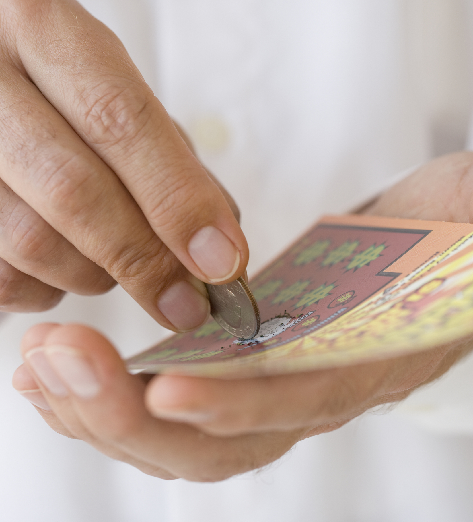 Person scratching a lottery ticket with a coin