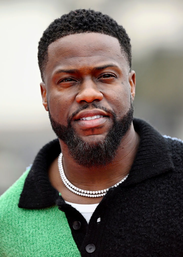 Kevin Hart wearing a green and black sweater with a white beaded necklace