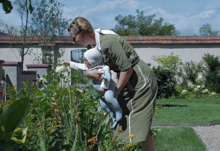 Woman holding a baby in a garden as the baby touches a flower