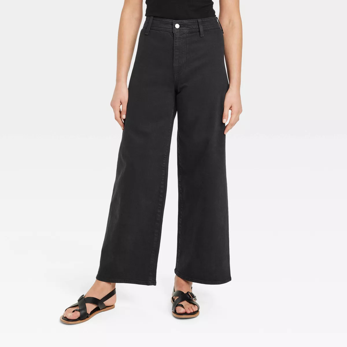 Wide-leg black jeans paired with strappy sandals, image focuses on lower half of the body