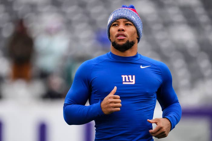Athlete in blue sportswear and woolen hat with a football team logo, running on a field