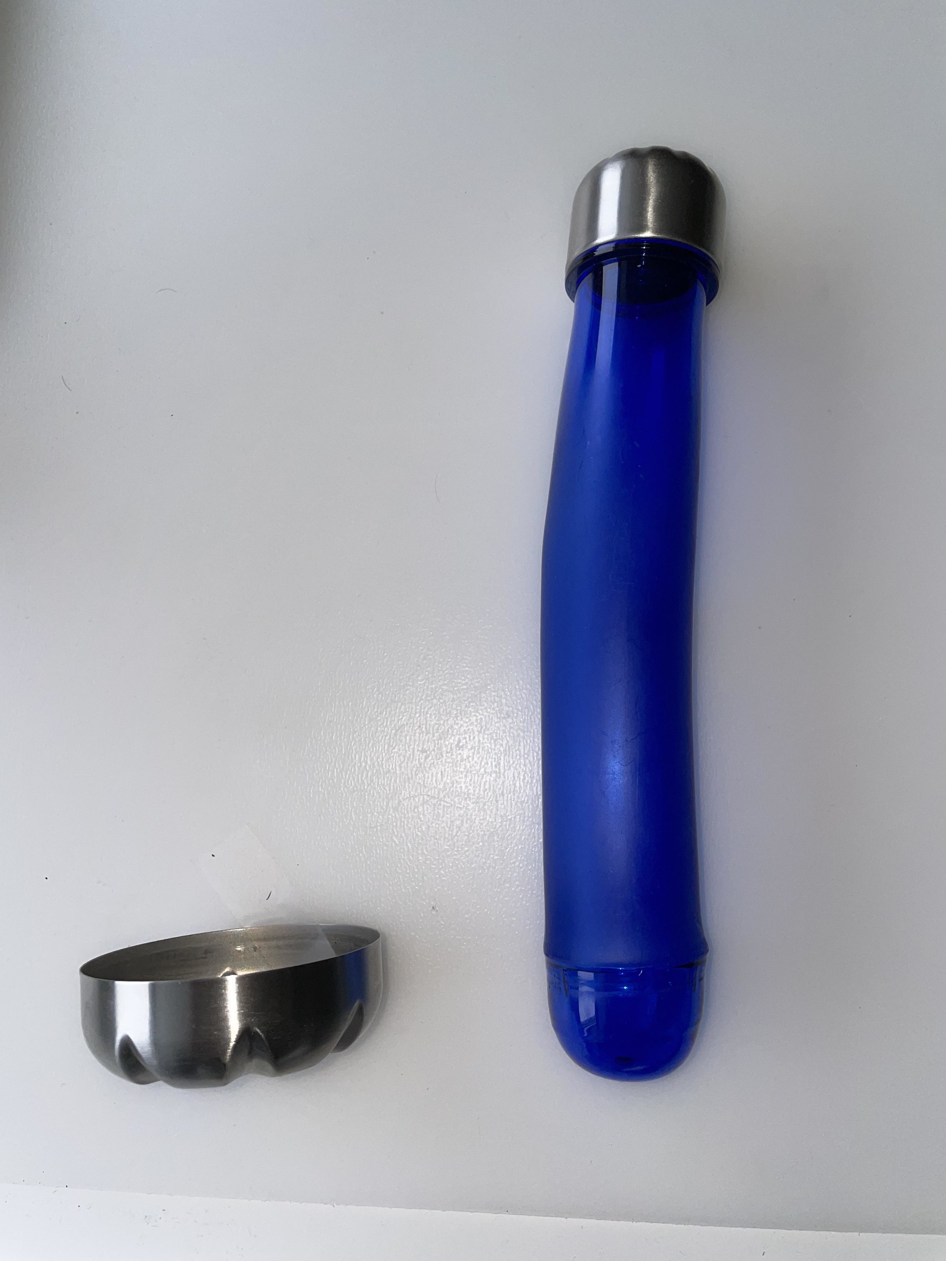 A long, blue tube with a metallic cap next to a separate silver-colored, wider round cap