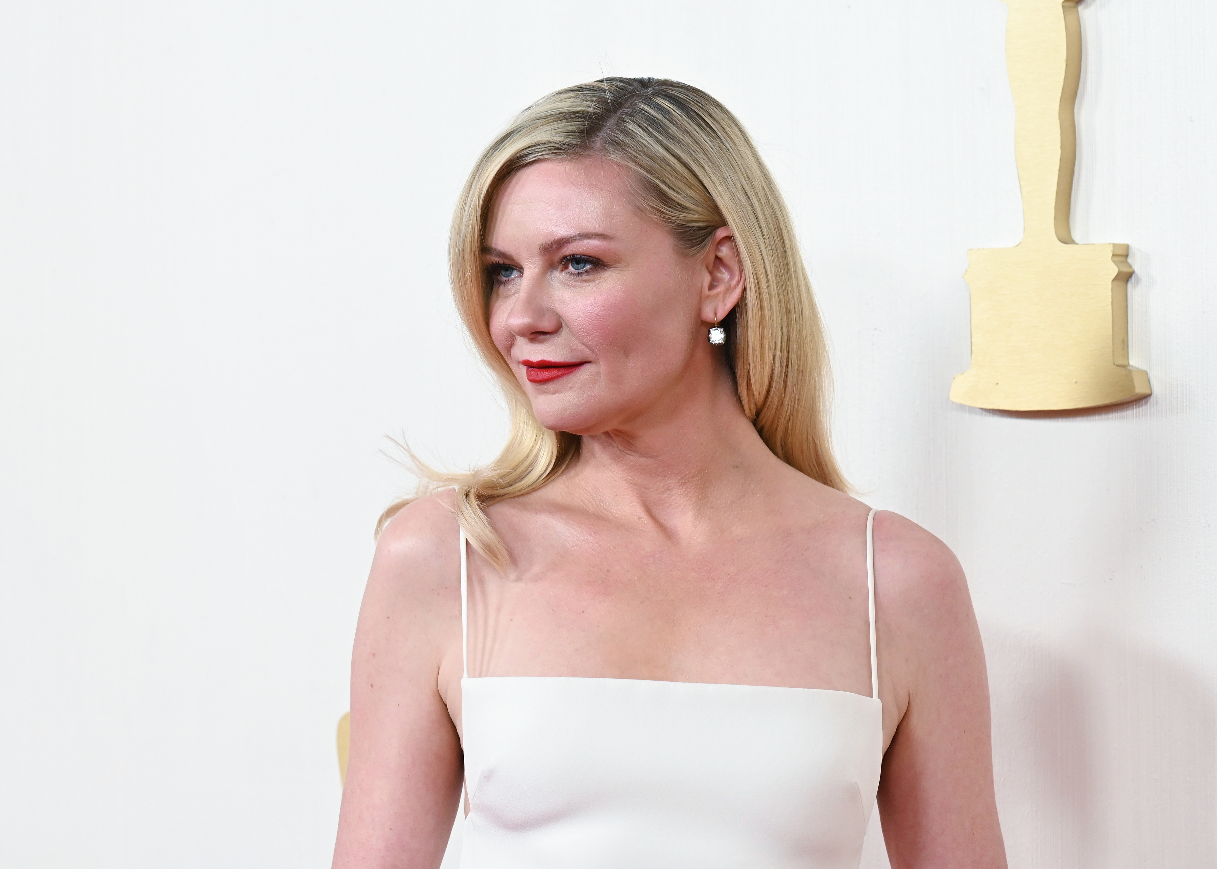 Kirsten Dunst at an event, wearing a sleek strapless dress, her hair styled to one side