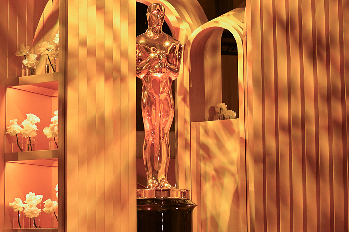 Oscar statue displayed among gold-toned decor with flowers, adding glitz to a pop culture event