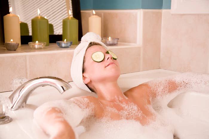 Woman relaxing in a bubble bath with cucumber slices on her eyes