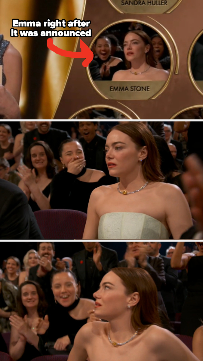 Emma Stone reacts with surprise at an event; she's seated, wearing a white dress with a sparkling necklace