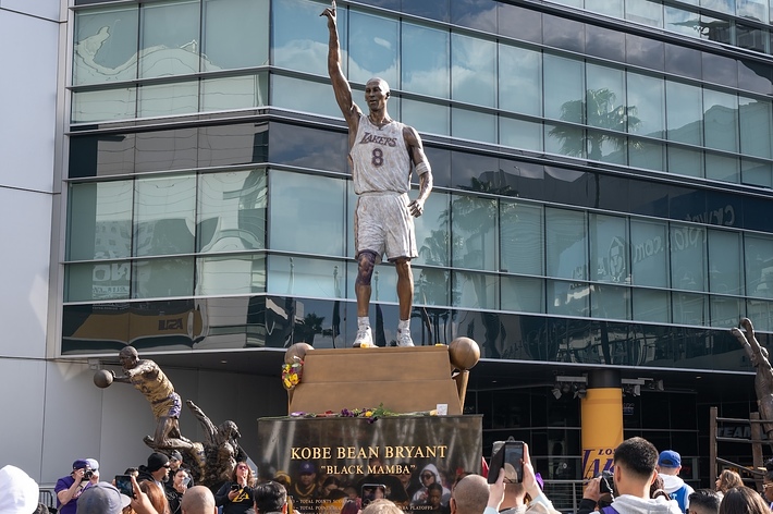 Statue of Kobe Bryant outside a building with spectators around