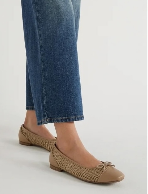 Woman wearing classic beige perforated ballet flats and blue denim jeans