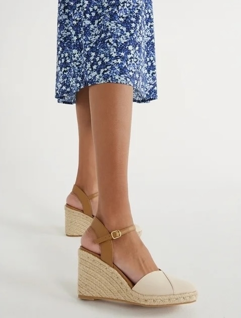 Person standing in wedge sandals with floral print skirt, focus on footwear for shopping context