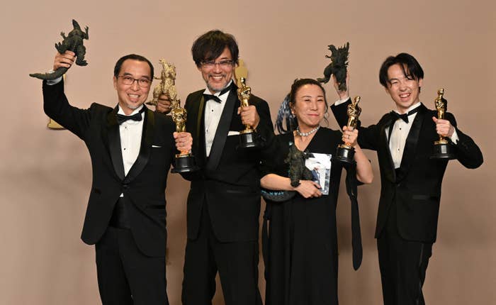 映画の賞を受賞した４人がトロフィーを持ち笑顔で立っている。