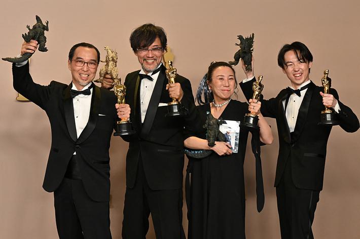 映画の賞を受賞した４人がトロフィーを持ち笑顔で立っている。