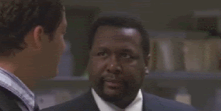 Two men in conversation, one making an expression of disbelief and nodding