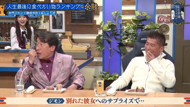 テレビ番組に登場する2人の男性と笑顔の女性。男性はお菓子を食べ、楽しそうな雰囲気。