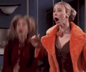 Two women expressing shock, one in an orange fur coat, hands near face