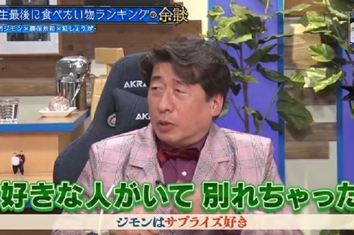 テレビ番組に出演している男性。背景には植物とロゴが見える。