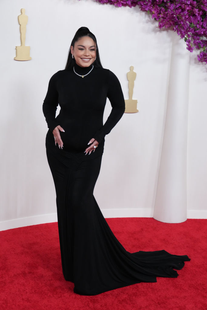 Vanessa Hudgens in elegant long-sleeve gown with a train posing on the red carpet