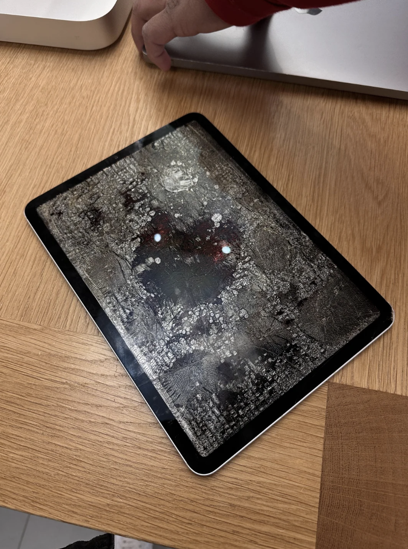A cracked tablet screen with a heartlike pattern and two glowing spots resembling eyes