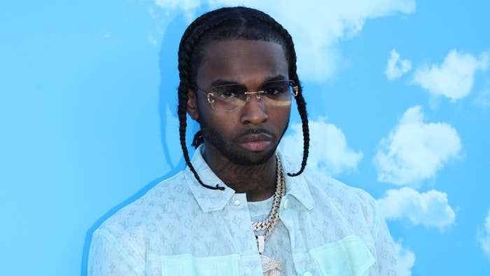 Pop artist in a light-patterned jacket and braided hair against a cloud backdrop