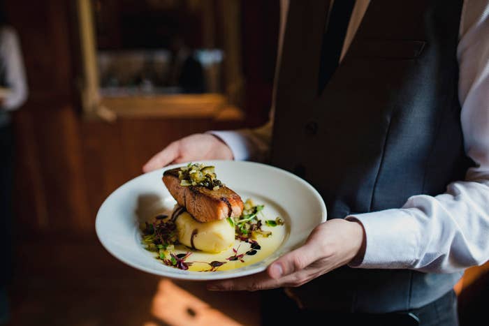 Server in suit presents a gourmet plated dish