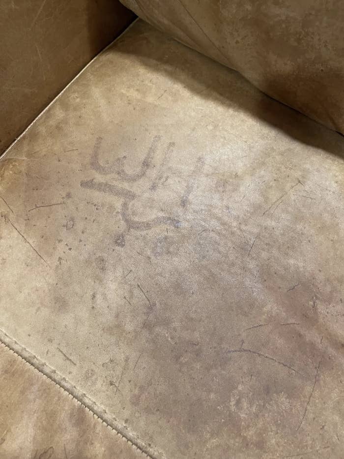 A worn couch cushion with an imprint resembling a cattle brand