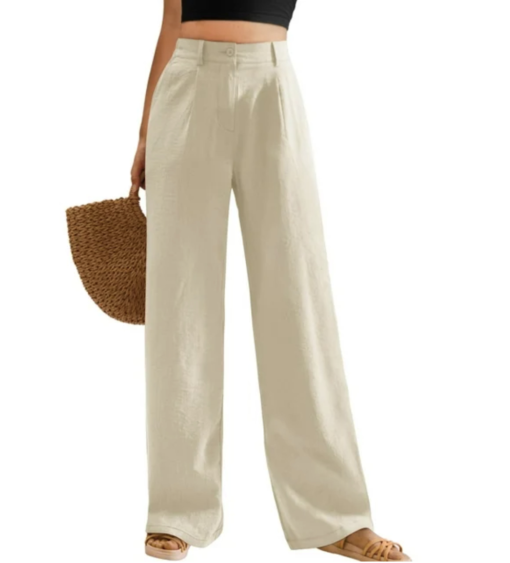Model wearing wide-leg trousers with sandals, holding a woven bag