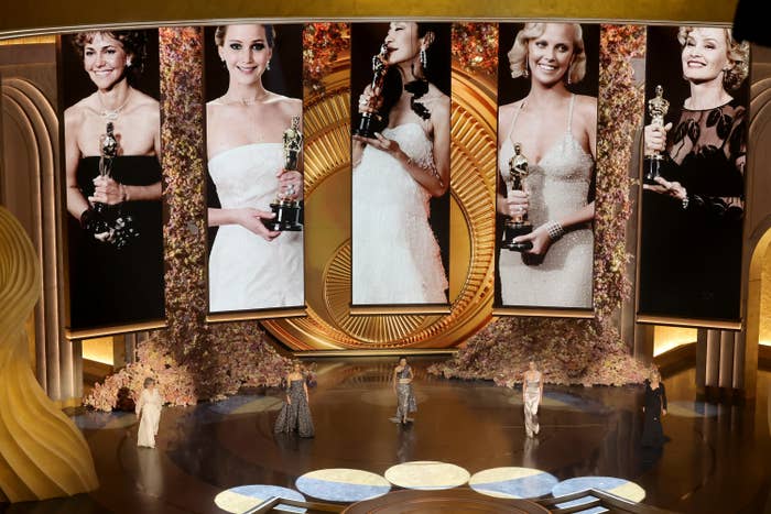 Award show stage with large screens displaying past female Oscar winners holding trophies