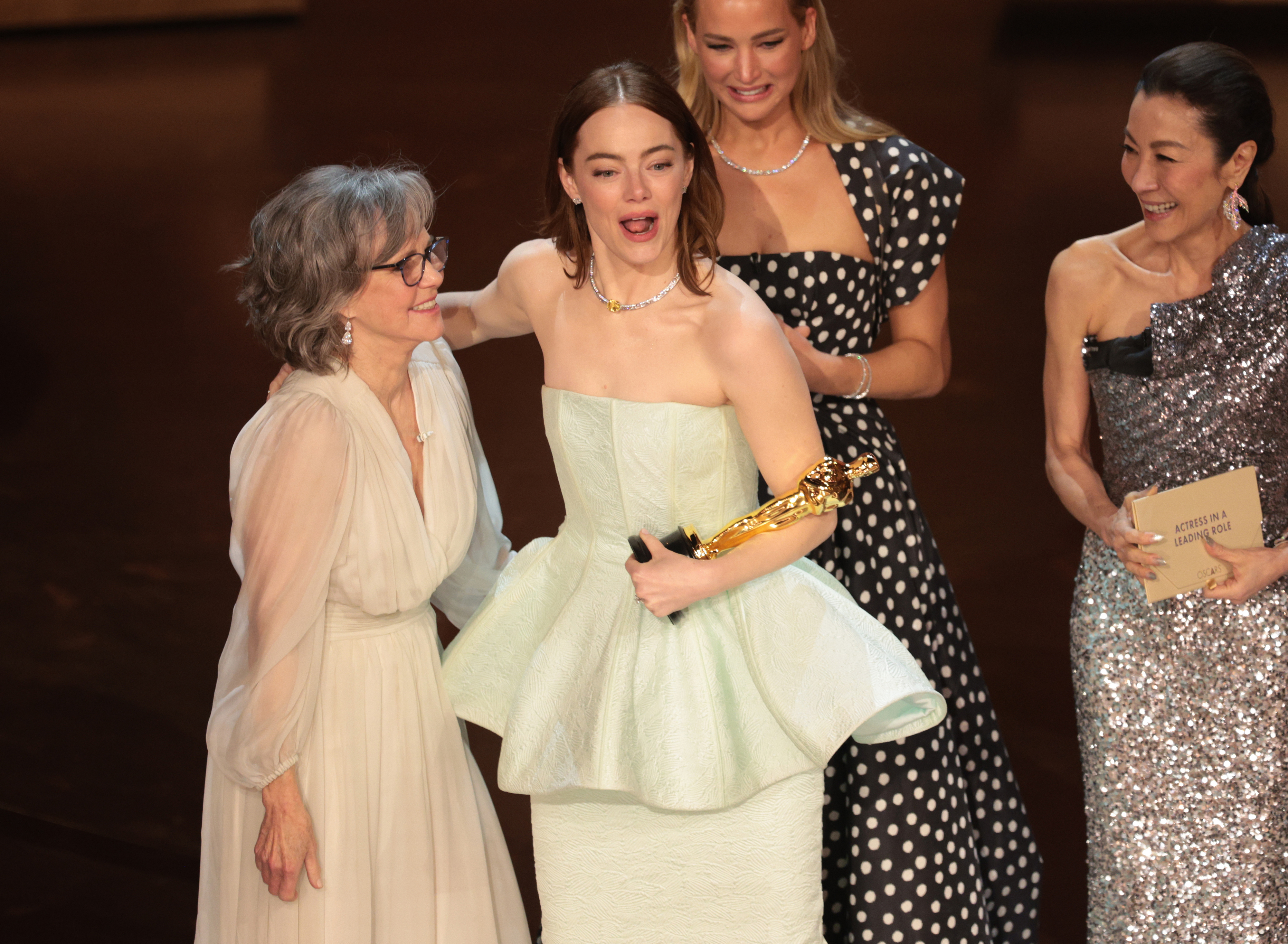 Emma Stone with her arm around Sally Field on the Oscars stage