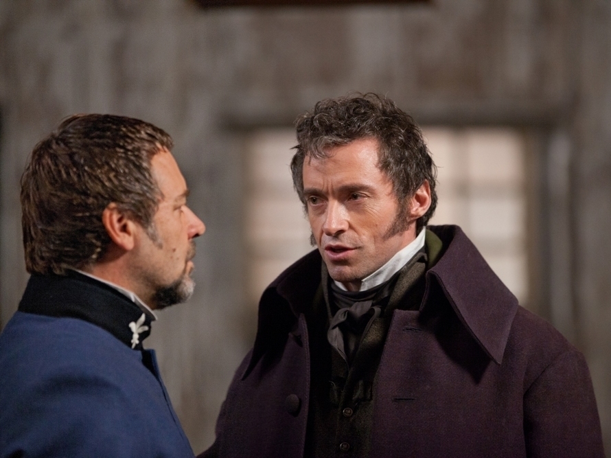 Two characters from Les Misérables in a tense scene, one in a navy coat and the other in a purple coat