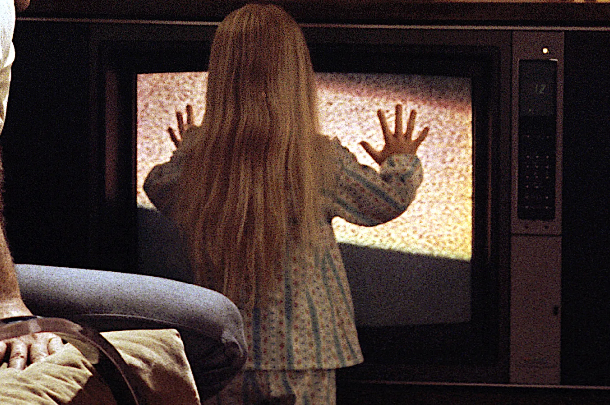 Child character from the TV movie &#x27;Poltergeist&#x27; touching a static-filled television screen