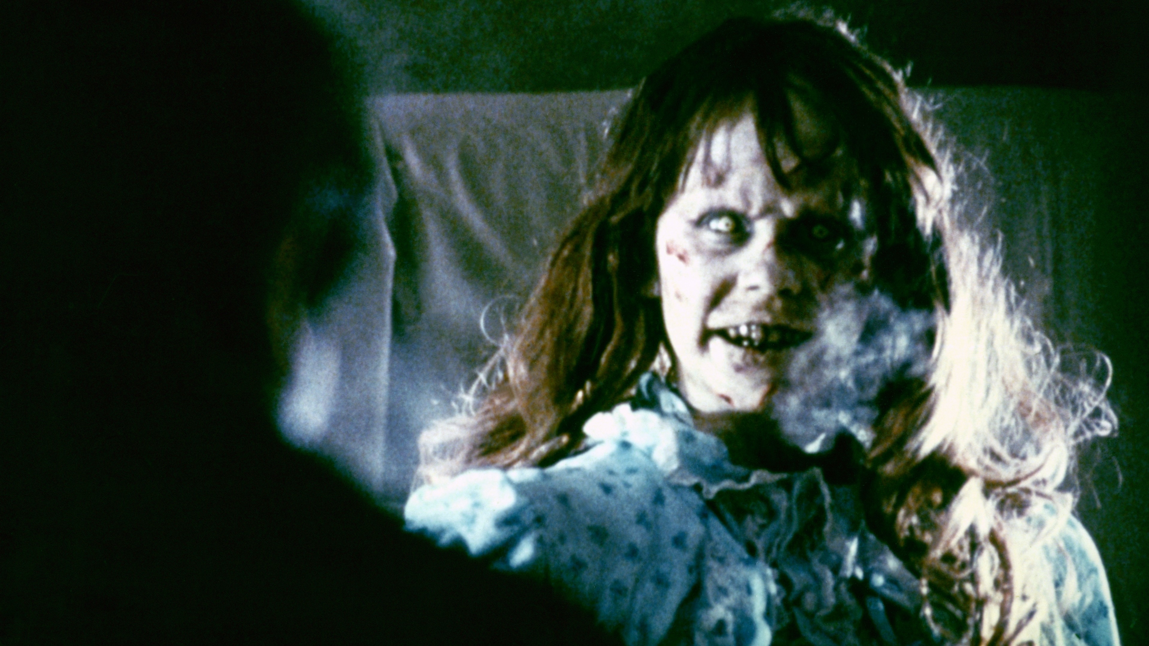 Character Regan from The Exorcist appears possessed in bed, facing an unseen figure