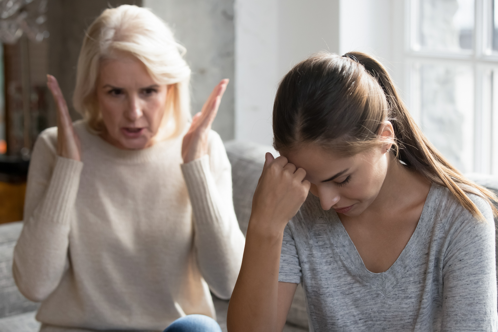 Older woman gesturing in frustration towards a young woman who looks stressed, possibly in a family disagreement