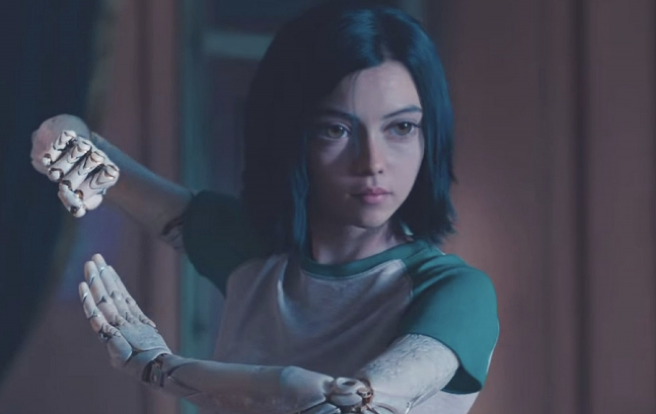 Character Alita from the movie &quot;Alita: Battle Angel&quot; examining her robotic hands indoors