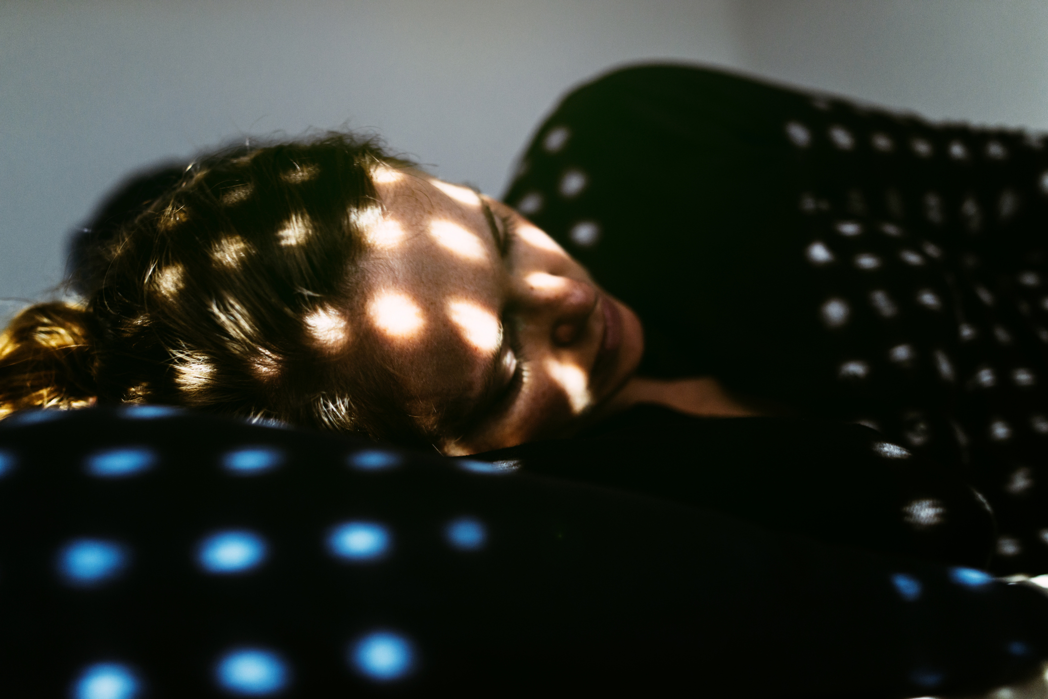 Person resting with dotted light patterns on their face and body, resembling a peaceful atmosphere